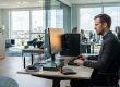 IT-tekniker arbejder med computer og netværksudstyr i et lyst kontor.